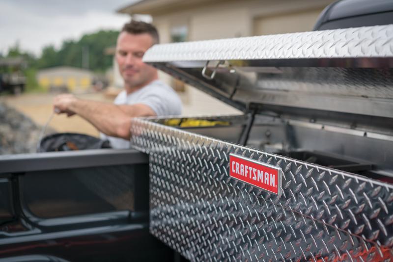 Right profile of 71 inch Brite aluminum full size truck tool box being used by a person to store accessories.