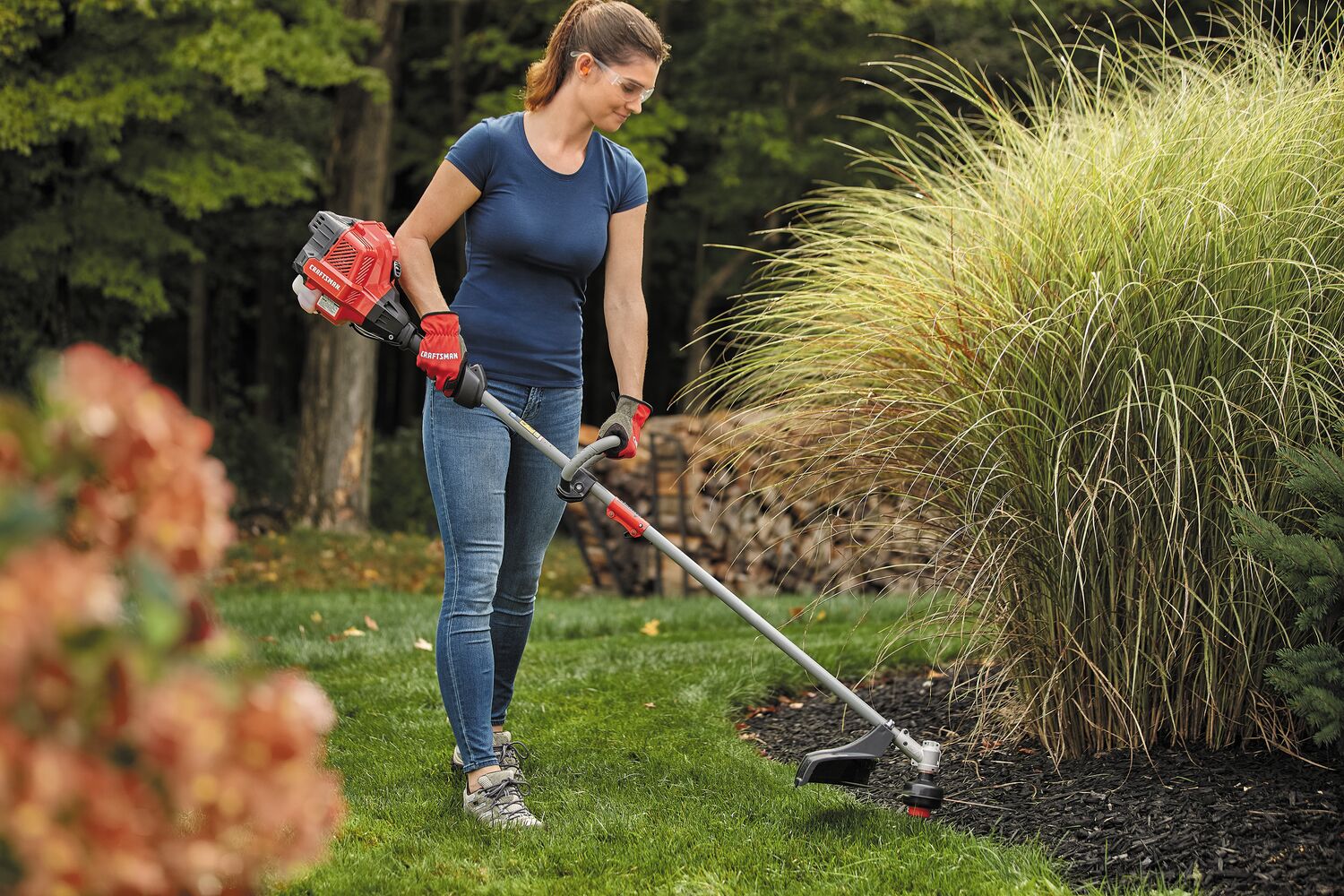 W S 2200 weedwacker 25 C C 2 cycle 17 inch attachment capable straight shaft gas trimmer being used by a person to trim grass.