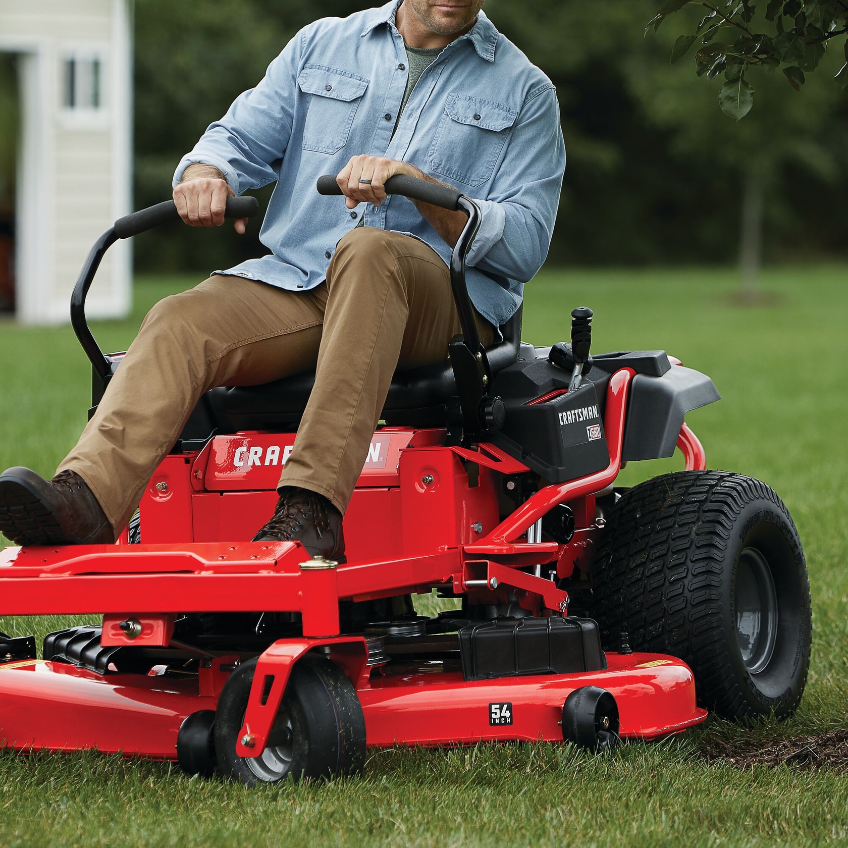 54 inch 24 h p zero turn riding mower being used by a person to mow the lawn.